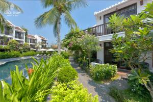 a resort with a swimming pool and palm trees at Hoi An Coco River Resort & Spa in Hoi An