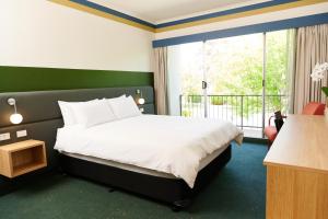a bedroom with a bed and a large window at Statesman Hotel in Canberra