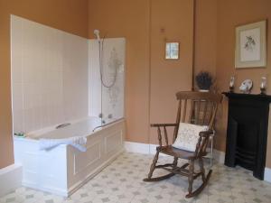 Cotton Farm في تشيستر: حمام مع حوض استحمام وكرسي هزاز