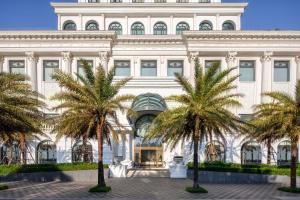 a large white building with palm trees in front of it at Melia Vinpearl Quang Binh in Dong Hoi