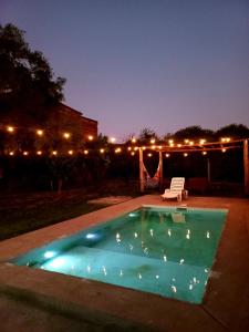 una piscina notturna con sedia e luci di Casa con piscina y patio a 20 minutos de la ciudad a Villa Dolores