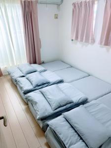 a row of beds in a room with a window at 海まで3分BBQテラス付き貸別荘 バケーションレンタルハウス Nalu resort Japan in Ichinomiya