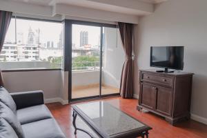 a living room with a couch and a flat screen tv at Forum Park Hotel in Bangkok