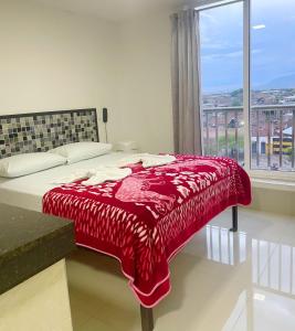 1 dormitorio con 1 cama con manta roja y ventana en Apartahotel El paraiso, en Cali