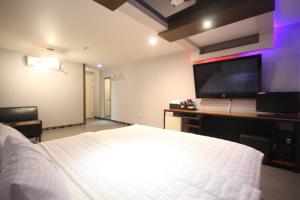 a bedroom with a large bed and a flat screen tv at v motel in Busan