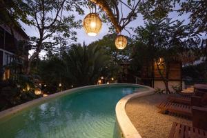 una piscina con 2 luces, sillas y árboles en Casa Selva Sayulita en Sayulita