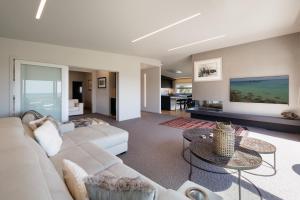 a living room with a white couch and tables at Luxury Ocean Villa in Papamoa in Papamoa