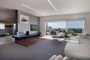 a living room with a couch and a tv at Luxury Ocean Villa in Papamoa in Papamoa