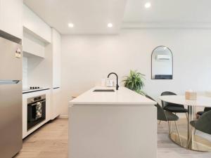 a kitchen with a white counter and a table at Brand new stylish 2BR apartment- free parking in Auckland