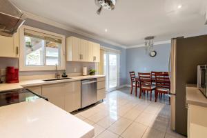 a kitchen with white cabinets and a table and chairs at CHEERFuL 2 LEVEL HOUSE 4 BED 3 BATH PARKiNG in Delta