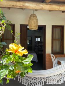 a hammock on the patio of a house with a yellow flower at Pousada da Praia in Garopaba