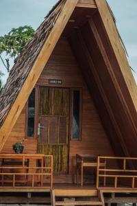 Cabaña de madera con puerta grande y bancos en Sinuan homestay- Jabu 02 en Pandanga