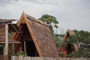 a house with a thatched roof behind a fence at Sinuan homestay- Jabu 02 in Pandanga