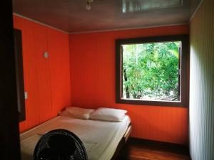 Habitación roja con cama y ventana en CASA VERO CAHUITA, A 100 M. DEL PARQUE NACIONAL, en Cahuita