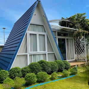 une maison avec un toit en gambrel et une terrasse couverte dans l'établissement Homestay Tulip Garden Bảo Lộc, à Bảo Lộc