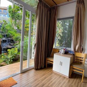 Cette chambre dispose d'une grande fenêtre, d'une table et de chaises. dans l'établissement Homestay Tulip Garden Bảo Lộc, à Bảo Lộc