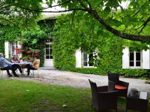 grupa ludzi siedzących przy stole przed domem w obiekcie Gîte spacieux avec jardin, piscine, cheminée, et équipements bébé au cœur des vignes du Cognac - FR-1-653-59 w mieście Lignières-Sonneville