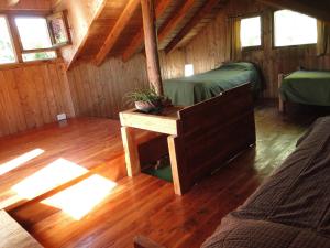 a room with two beds and a table in a cabin at Abedules in Dina Huapi