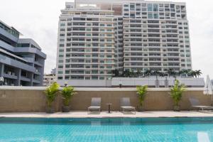 a pool with two chairs and two tall buildings at Forum Park Hotel in Bangkok