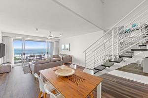 a living room with a table and a staircase at La Mer Sunshine Beachfront in Sunshine Beach