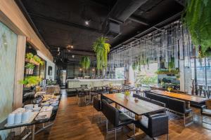 un restaurante con mesas de madera, sillas y plantas en Forum Park Hotel en Bangkok