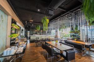 un restaurant avec des tables et des chaises en bois et des plantes dans l'établissement Forum Park Hotel, à Bangkok