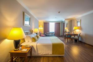 Habitación de hotel con cama grande y escritorio. en Golden Tulip Sovereign Hotel Bangkok, en Bangkok