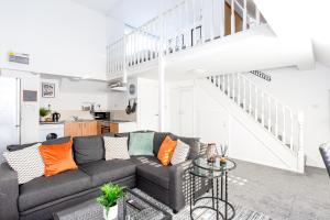 a living room with a black couch and a staircase at Elmsleigh Lofts by Sorted Stay in Southend-on-Sea