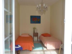 two beds in a room with a chandelier at Gîte paisible avec jardins privatifs à Cognac, proche des sentiers de randonnée, animaux acceptés - FR-1-653-178 in Cognac