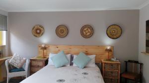 a bedroom with a bed with four plates on the wall at A1 Kynaston self catering or bed and breakfast solarpower in Jeffreys Bay