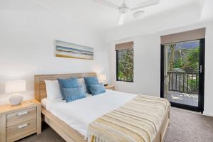 a bedroom with a large bed with blue pillows at Elysium Apartments in Palm Cove