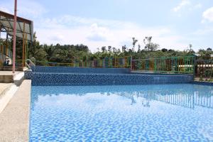a swimming pool with blue water and a fence at Happy Valley Eco Farm in Kerling