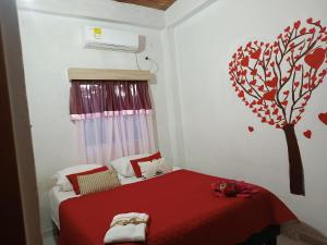een slaapkamer met een rood bed met een boom aan de muur bij Hotel Veraneras in Santa Veronica