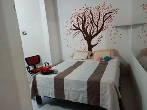 een slaapkamer met een bed met een boom aan de muur bij Hotel Veraneras in Santa Veronica
