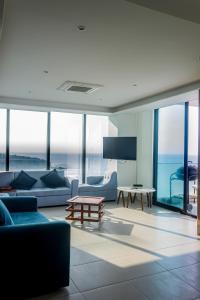 una sala de estar con muebles azules y ventanas de cristal. en Departamento Suite frente al mar Poseidon Manta en Manta
