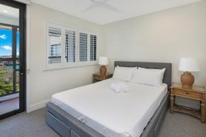 a bedroom with a white bed and a window at TARA7- On Trend At Taranaki in Mooloolaba