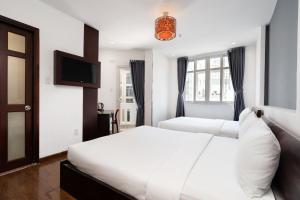 a bedroom with two beds and a flat screen tv at A&A Toronto Hotel in Ho Chi Minh City