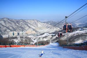a person skiing down a snow covered slope next to a ski lift at Sono Felice Village Vivaldi Park in Hongcheon