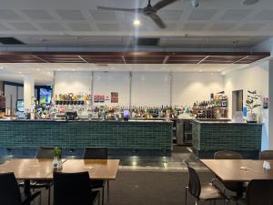 a restaurant with tables and chairs and a bar at Plantation Hotel Coffs Harbour in Coffs Harbour