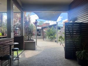 eine Terrasse mit Pflanzen, einem Tisch und Stühlen in der Unterkunft Plantation Hotel Coffs Harbour in Coffs Harbour