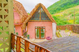 una pequeña casa rosa con techo de paja en Casa Mambo Salinas, en Santa Verónica