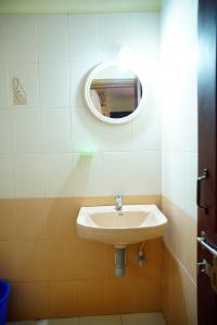a bathroom with a sink and a mirror on the wall at Vrindavan Suites Guruvayur in Guruvāyūr