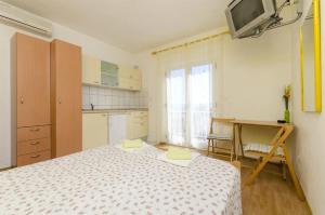 Schlafzimmer mit einem Bett, einem Schreibtisch und einem TV in der Unterkunft Apartments and rooms Mini - parking in Bol