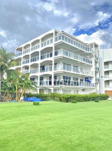 a large white building with a lawn in front of it at Maho Beach House - Spacious 1 Bedroom Suite in Maho Reef