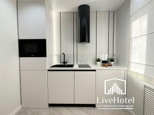 a kitchen with white cabinets and a sink at LUX на берегу Иртыша in Pavlodar