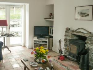 a living room with a fireplace and a television at Sqlarran Cottage in Lochranza