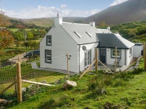 a white house with a fence in front of it at Sqlarran Cottage in Lochranza