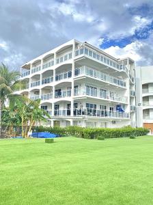 um grande edifício branco com um relvado em frente em Sunset Beach Condo - Luxury 1BR Suite next to The Morgan Resort em Maho Reef