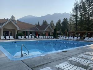 a large swimming pool with white chairs and a house at RidgeView Resort in Radium Hot Springs