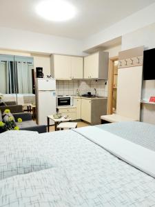 a bedroom with a white bed and a kitchen at PEARL STUDIO free private parking in Thessaloniki